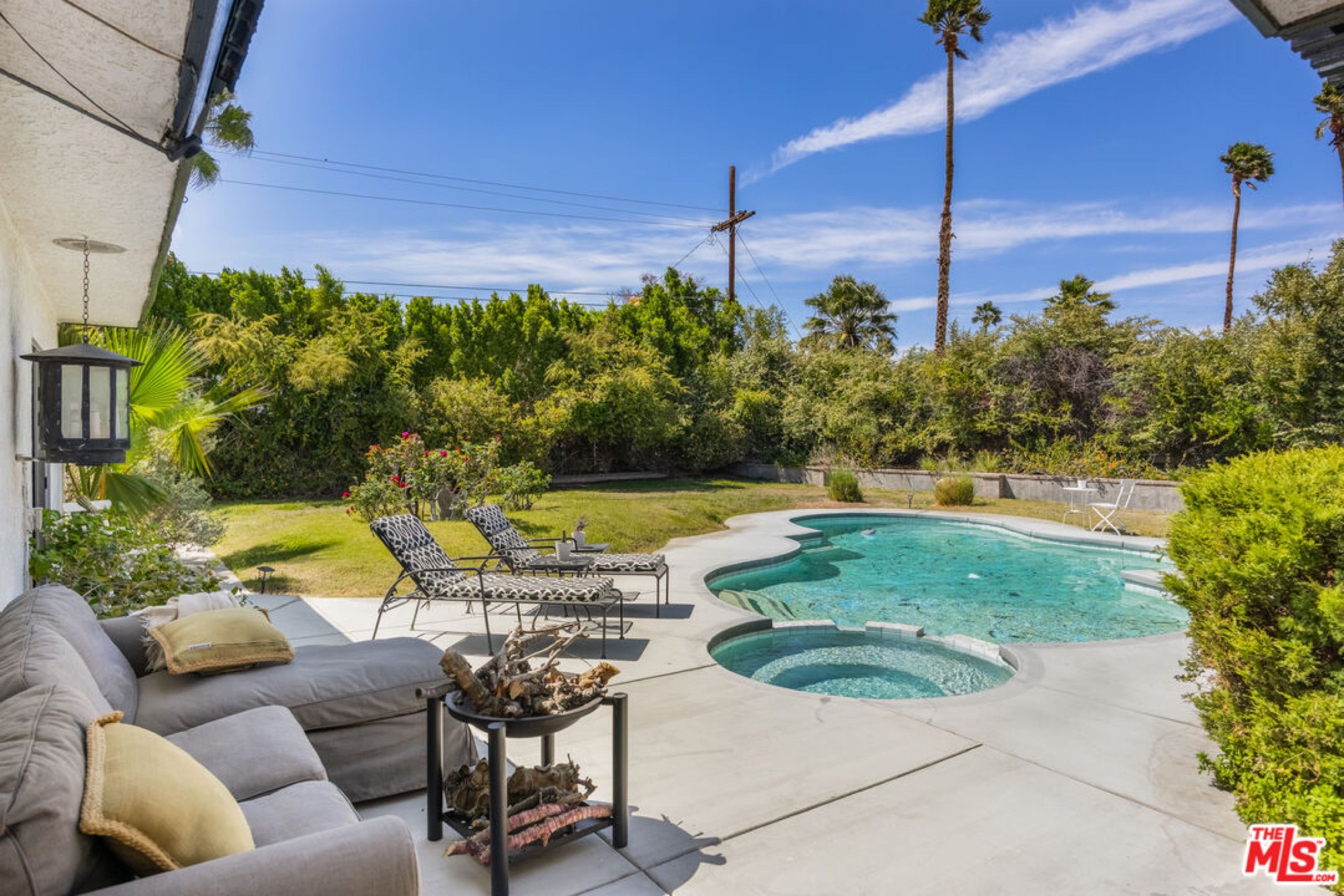 Pool and spa with outdoor seating under palm trees