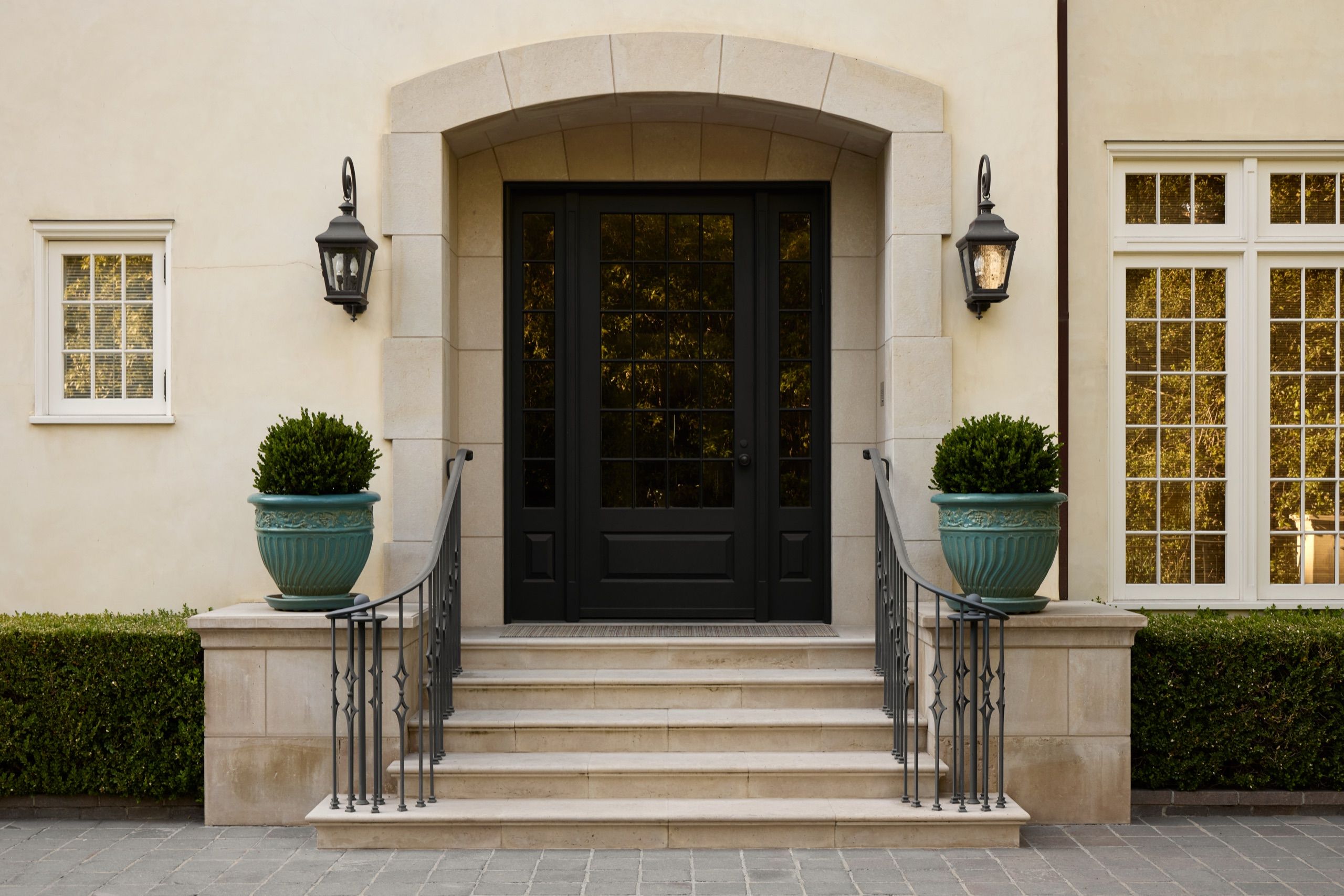 Limestone entry with black double doors and lanterns