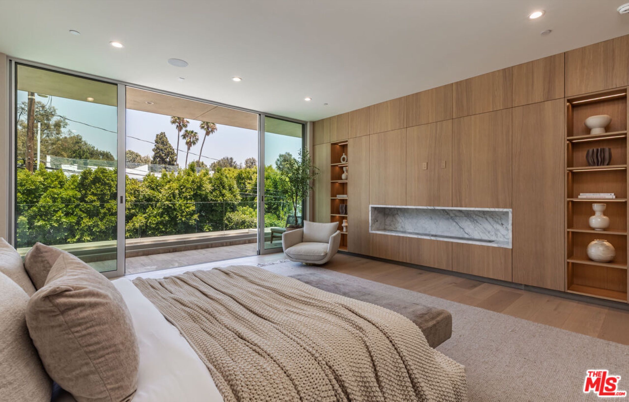 Primary bedroom with marble fireplace and floor to ceiling glass