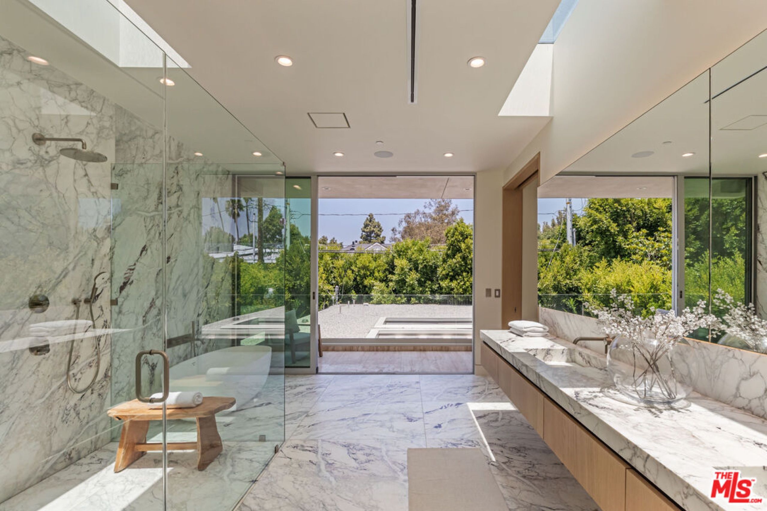 Primary bath opening to a terrace with garden views