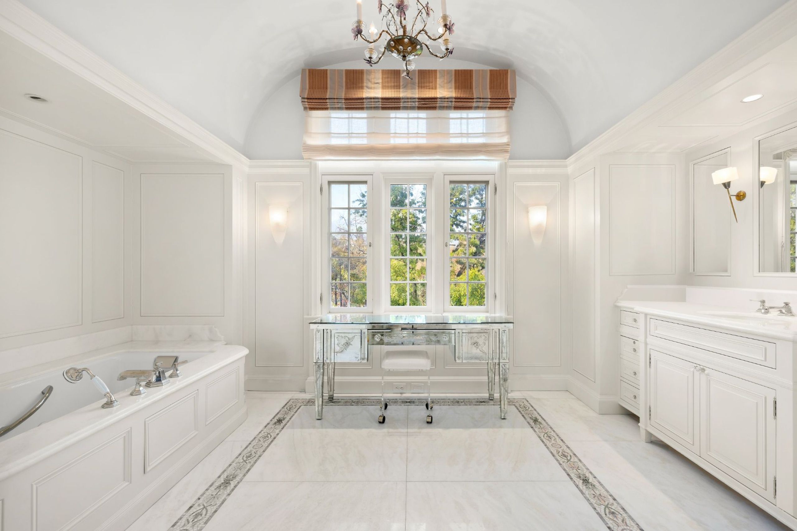 Primary bath in white marble with vaulted ceiling and soaking tub