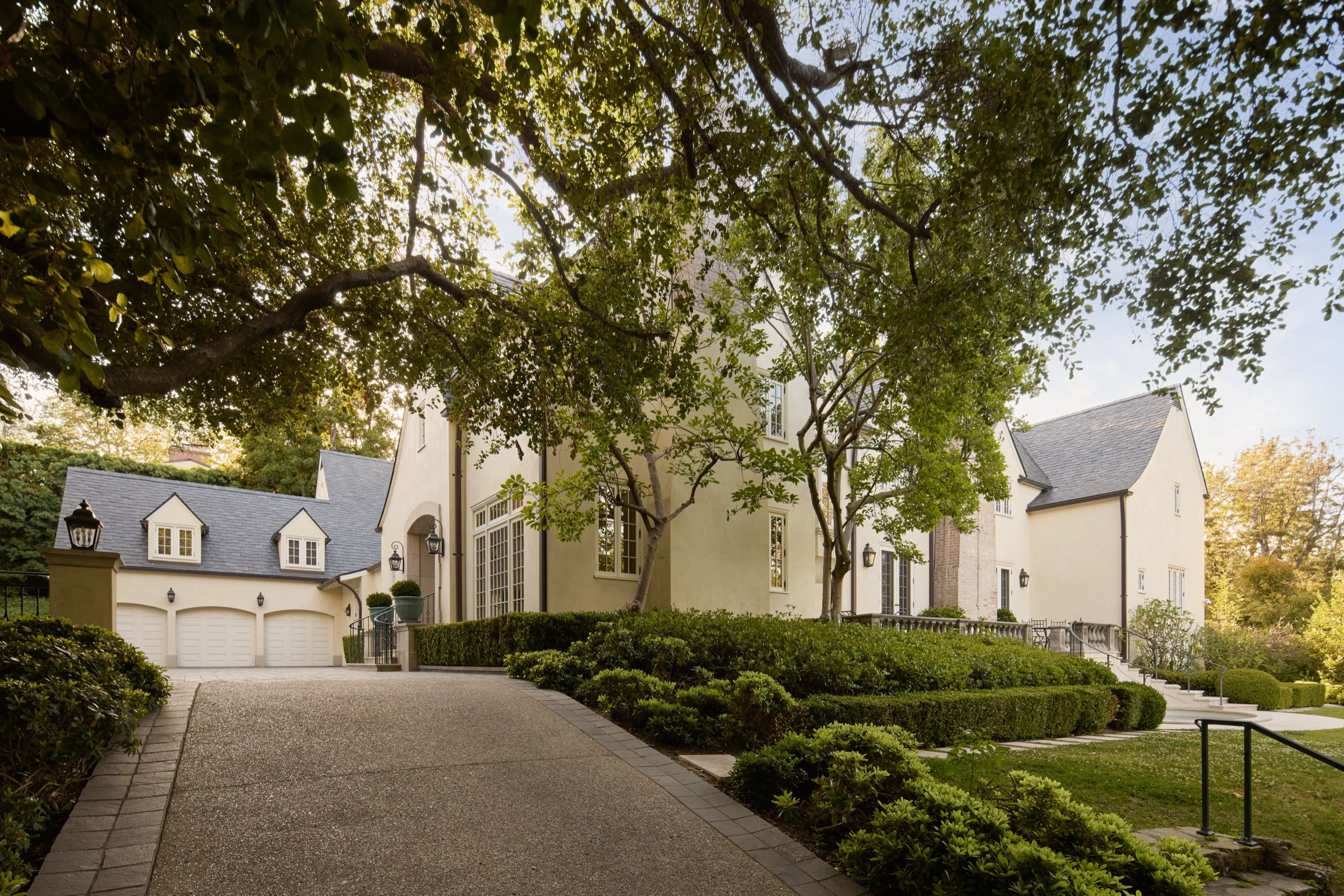 Gated motor court and garages beneath mature oaks